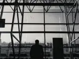 Person waiting airport lounge looking at aeroplanes